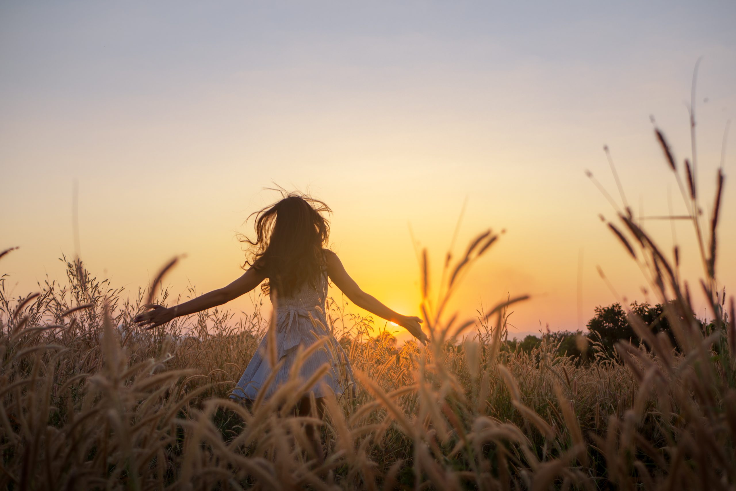 Trendy girl in stylish summer dress feeling free in the field with flowers in sunshine,enjoying nature, Beautiful Teenage Model in the Spring Field, Sun Light.